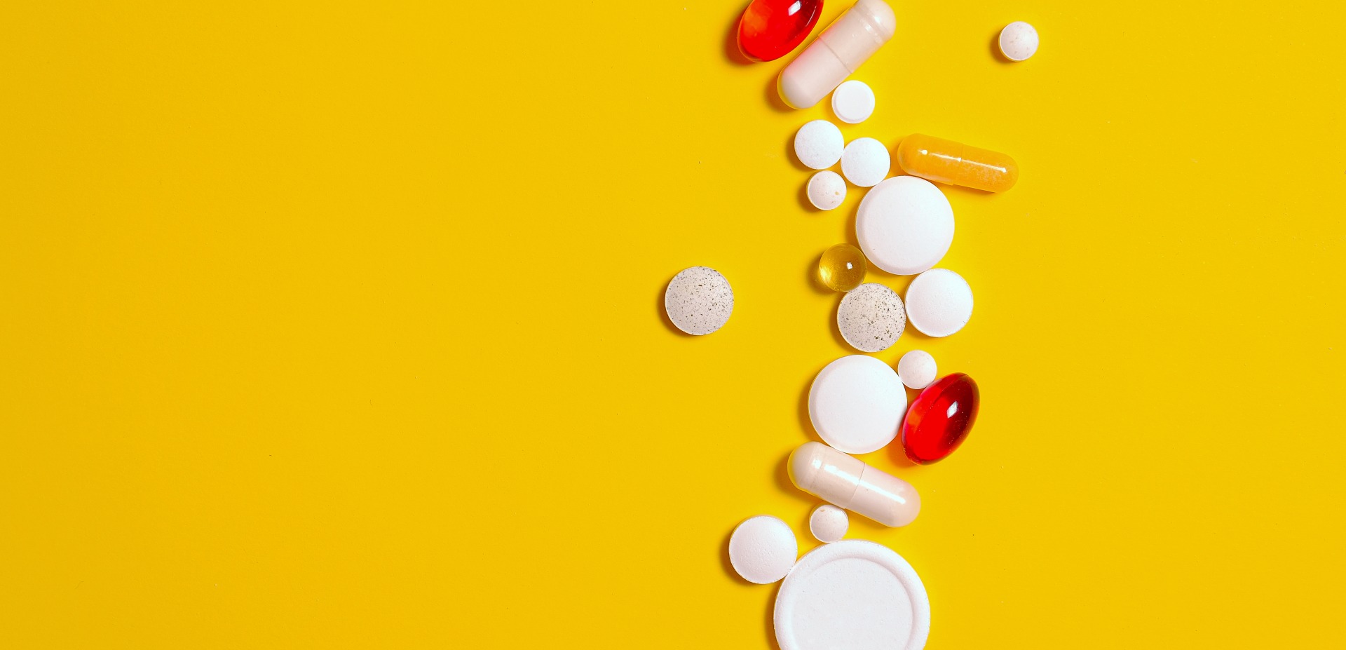 A selection of different pills on a yellow background.