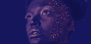 A tinted photo of a head with golden glitter sprinkled on the right side of the face.