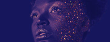 A tinted photo of a head with golden glitter sprinkled on the right side of the face.