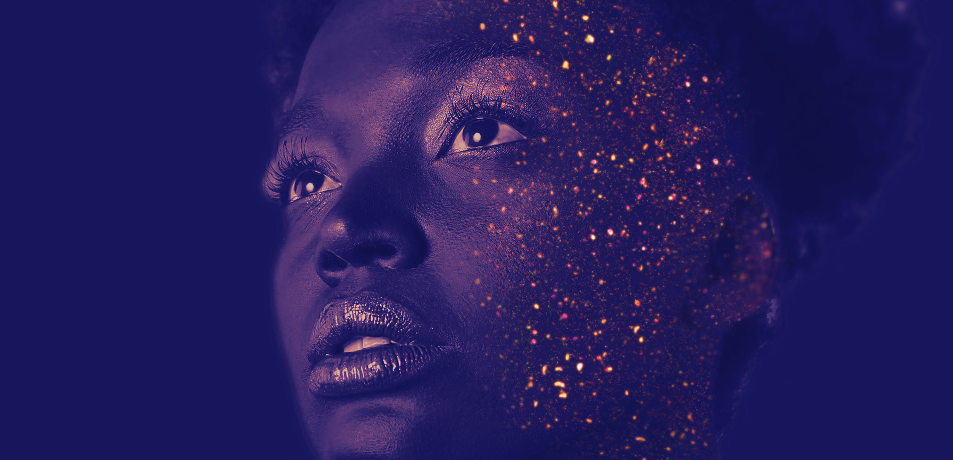 A tinted photo of a head with golden glitter sprinkled on the right side of the face.