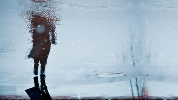 A photo of a person mirrored by a puddle.