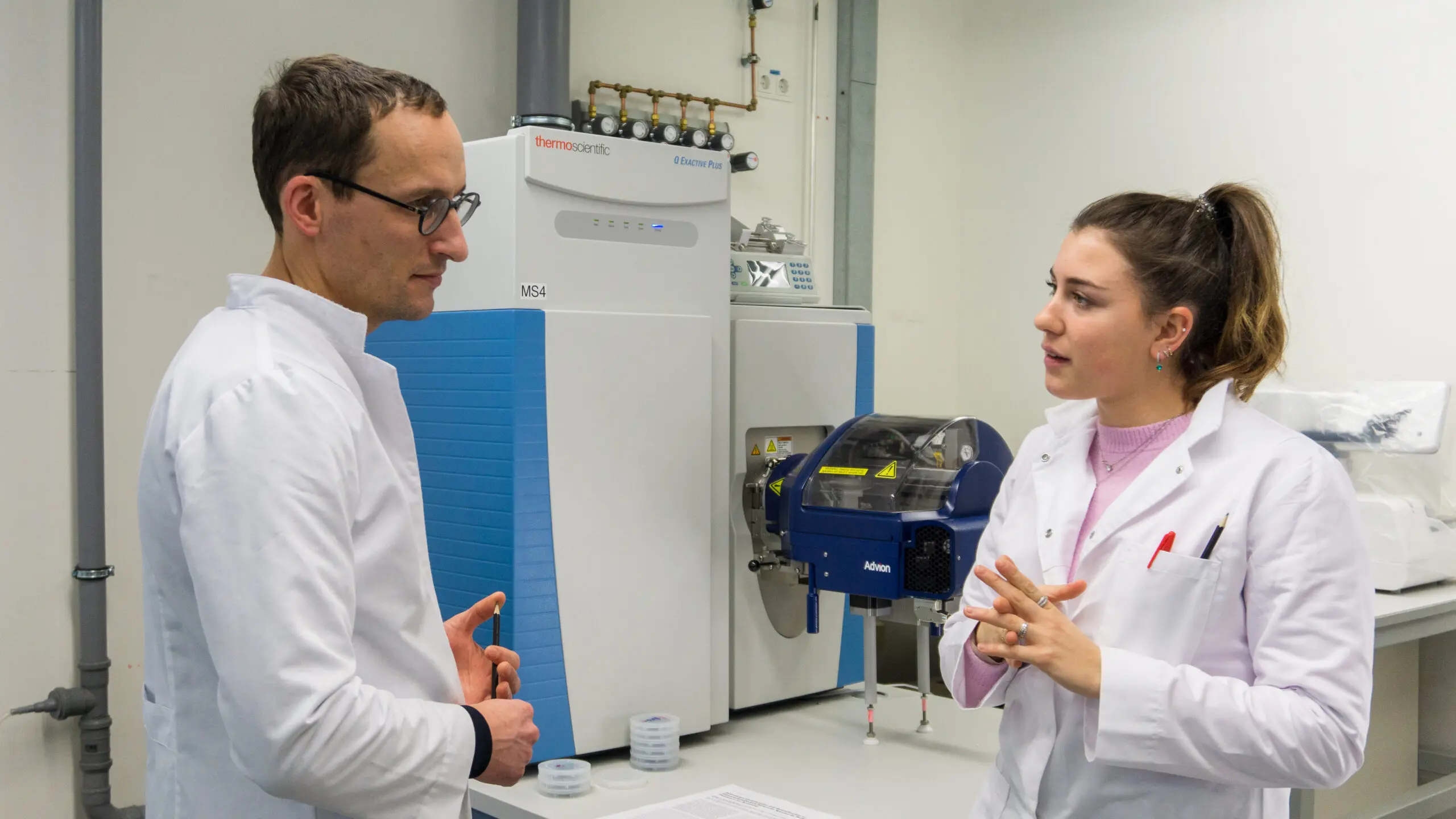 Scientists discussing in front of mass spectrometry. Scientists discussing in front of mass spectrometry.