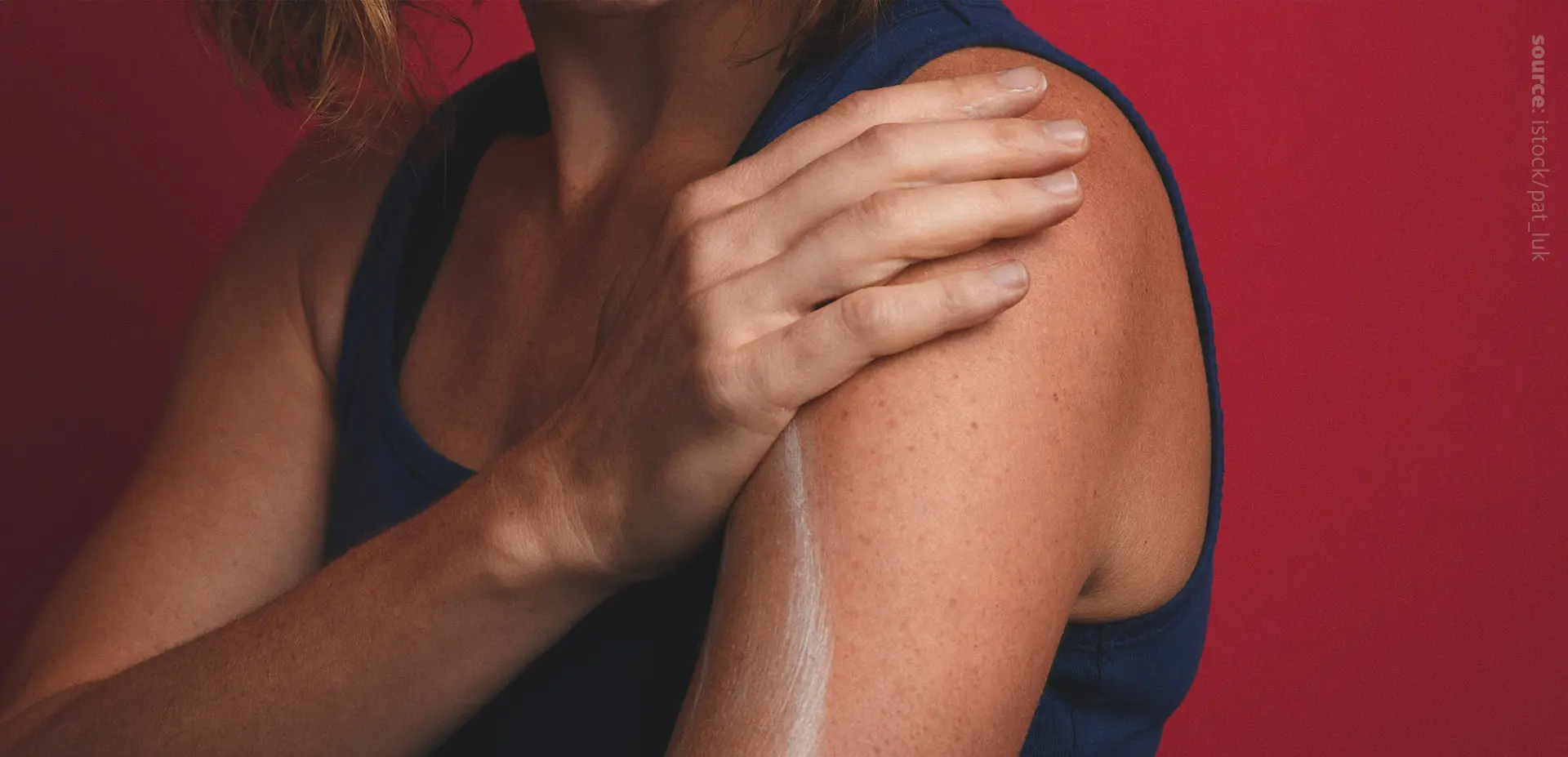 A photo of a person applying a cream on their shoulder.