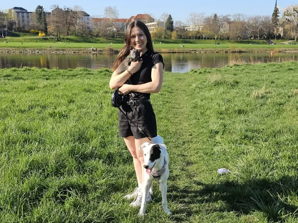 A girl is holding a dog and smiling